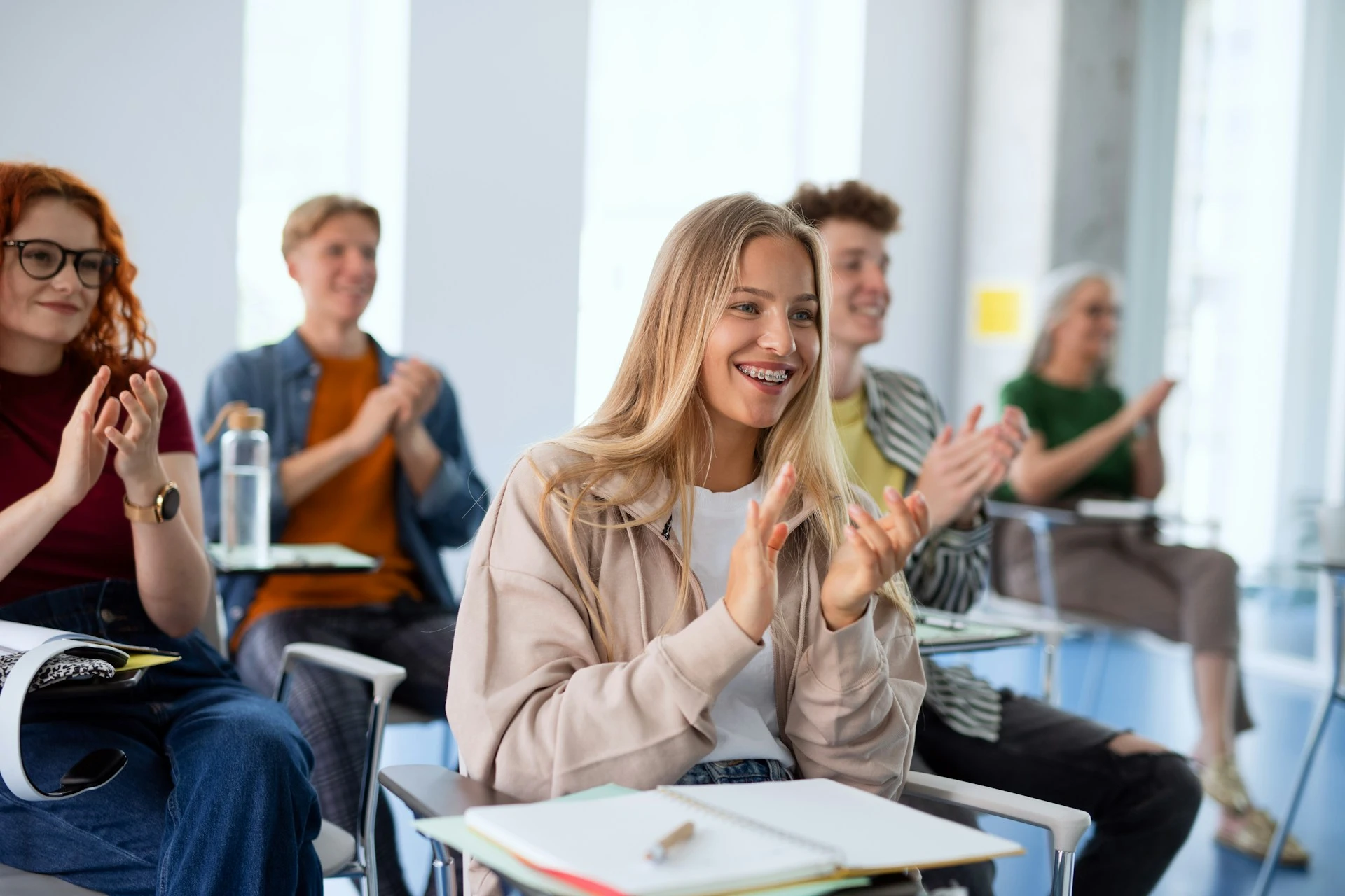 A female student applauding during class amongst other students